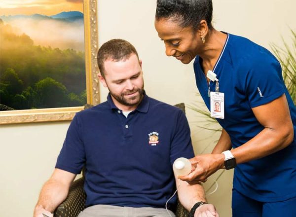 A nurse helps a man get a home infusion
