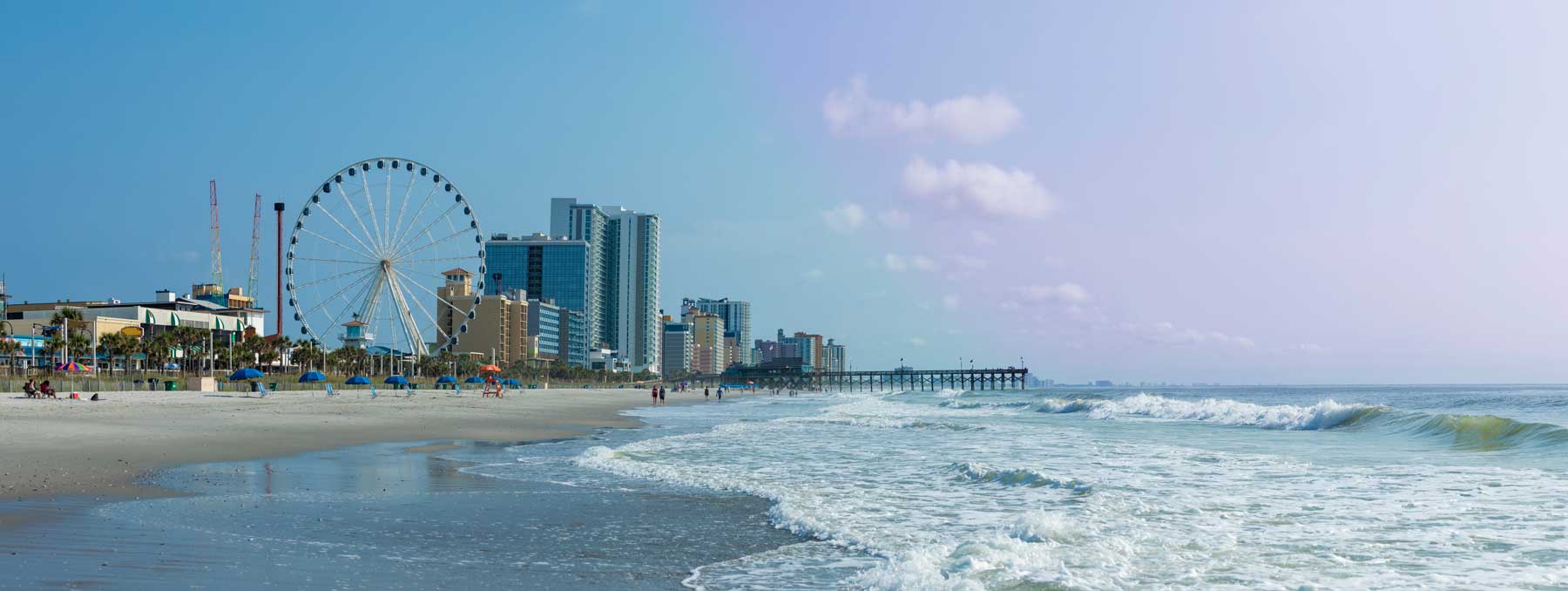 Panoramic view of Myrtle Beach, South Carolina with beach, hotels, ferris wheel, and boardwalk.